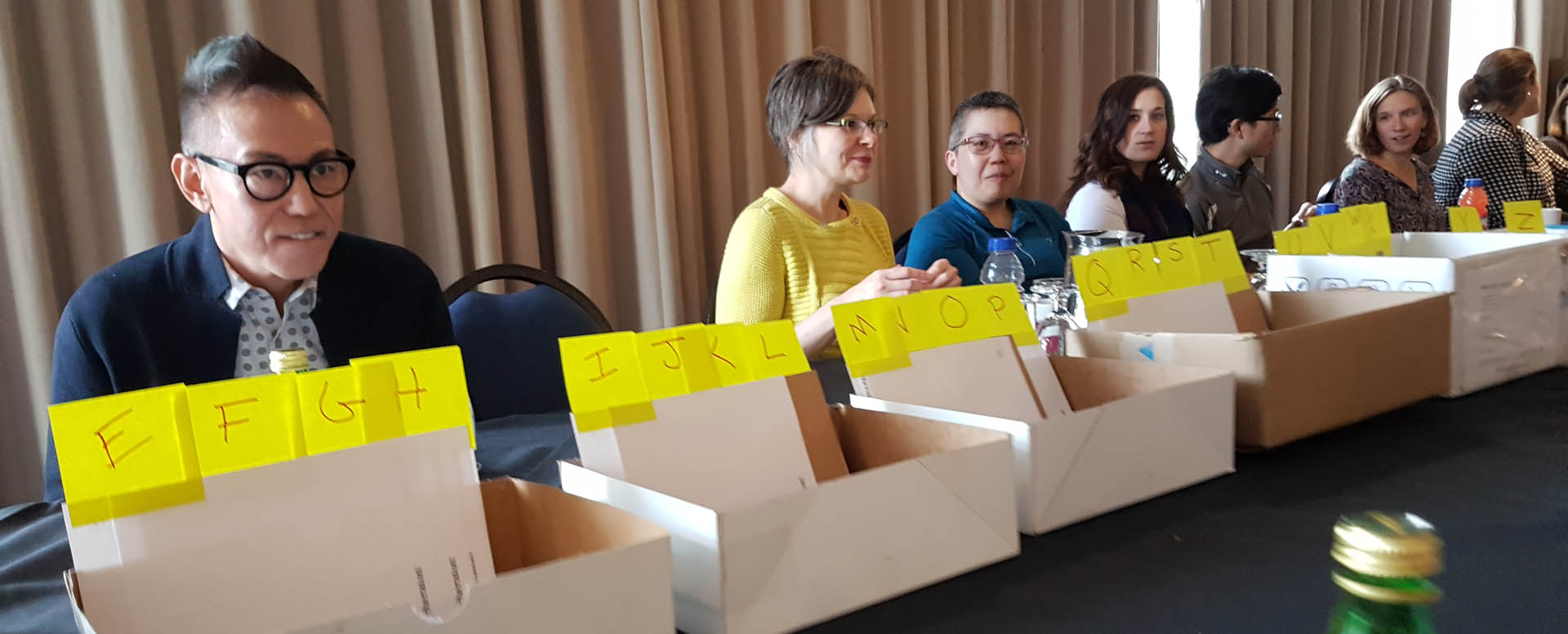 A group of volunteers sits at a table and sorts packets at the 2018 conference in Vancouver. 