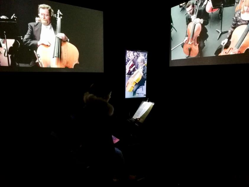 A man sits in a room with a virtual orchestra.
