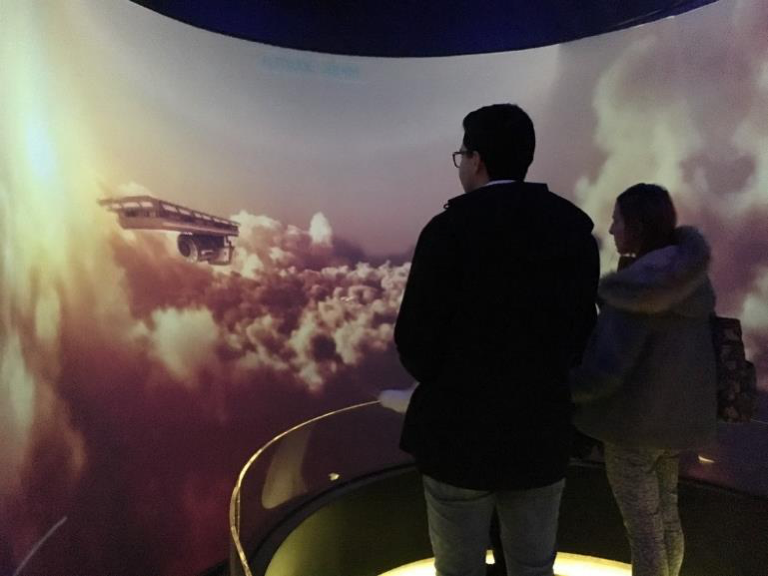 People stand in front of a screen, showing swirling dust