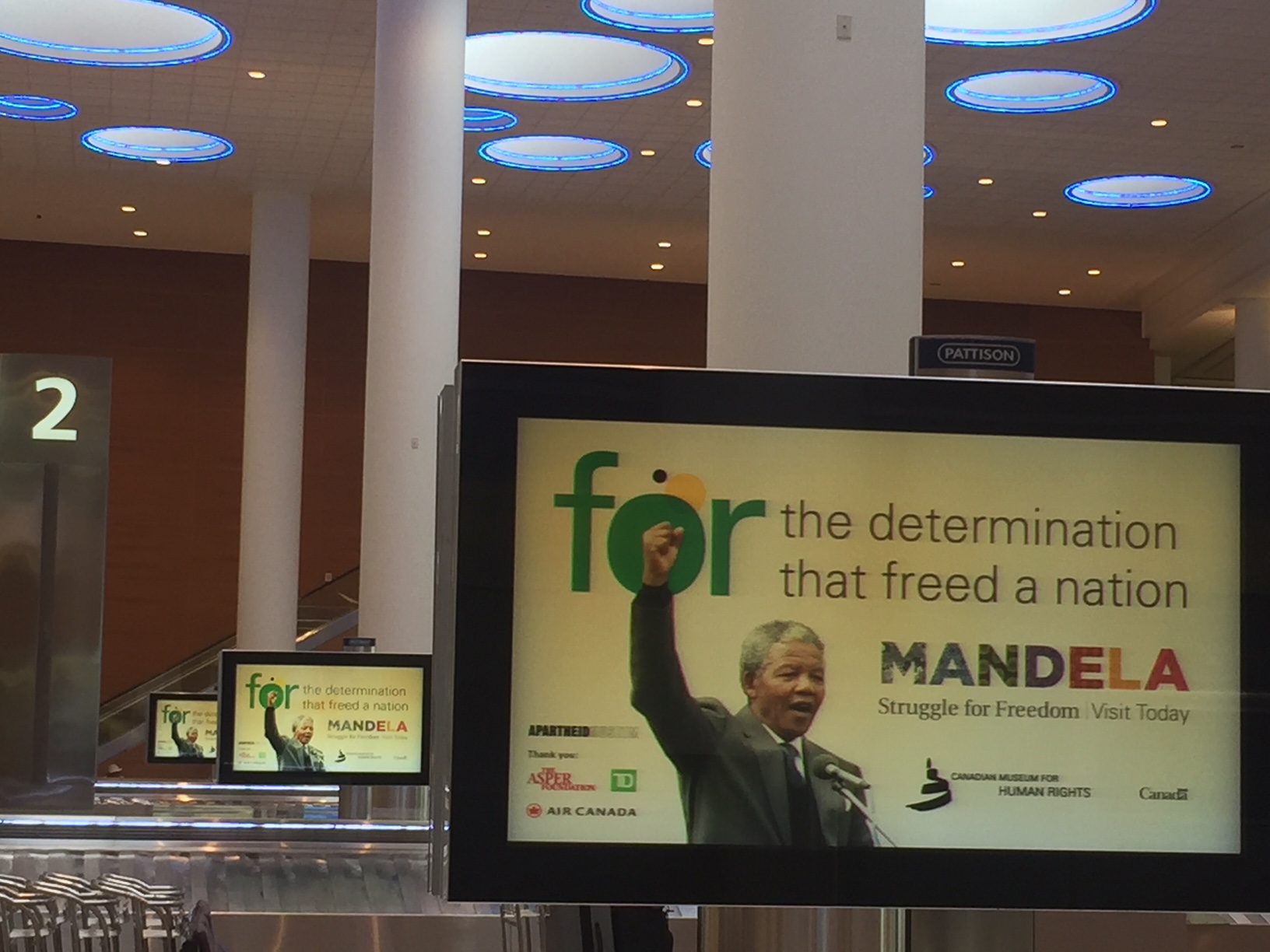 Baggage carousels featuring multiple screens with Mandela raising his fist.