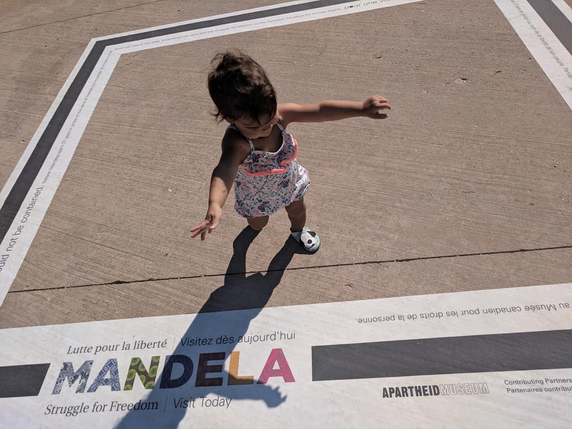 Small child walking on a concrete sidewalk with a large decal on it.